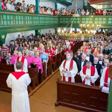 Vollbesetzte Kirche mit Pfarrer und Jugendlichen