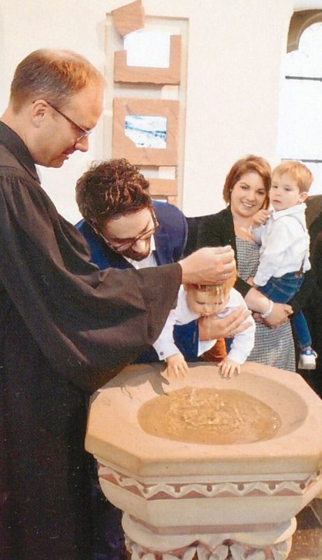 In der Martin-Luther-Kirche Detmold tauft Pfarrer Kruschke ein Kleinkind am Taufstein